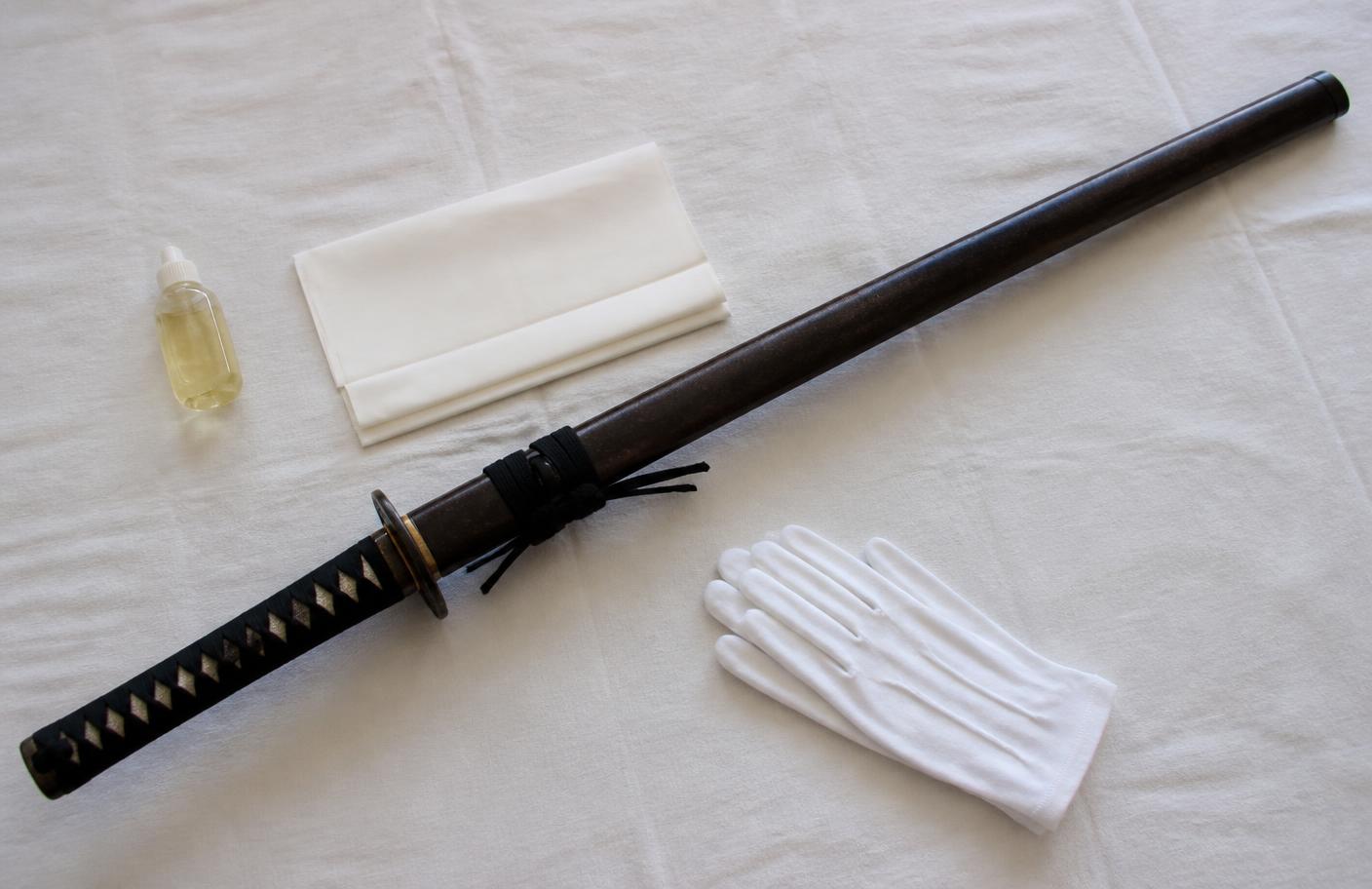 Sheathed Japanese-style sword with plain care supplies and handling gloves